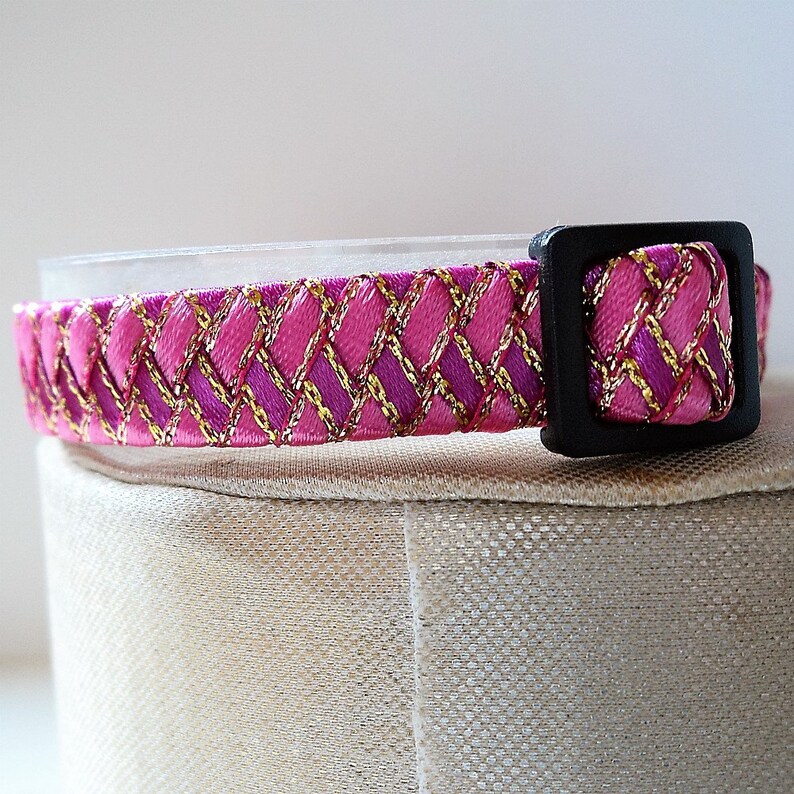 May include: Pink and gold patterned cat collar with a black plastic buckle.