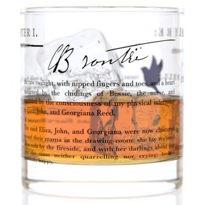 May include: A clear glass tumbler with a brown liquid inside. The glass has text printed on it, including the words "Chapter I." and "Brontre".