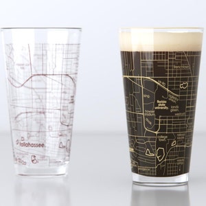 May include: Two clear pint glasses with a map design. One glass is empty, the other is filled with dark beer and foam. The map design is of Tallahassee, Florida, with street names and landmarks.