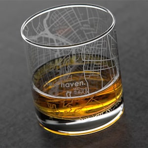 May include: A clear glass with an etched design of the New Haven, Connecticut city map. The glass is filled with a golden amber liquid.