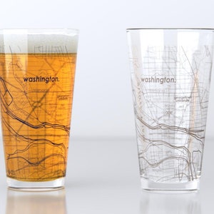 May include: Two clear pint glasses with a map of Washington, D.C. printed on them. One glass is filled with beer, the other is empty. The word "washington." is printed on each glass.