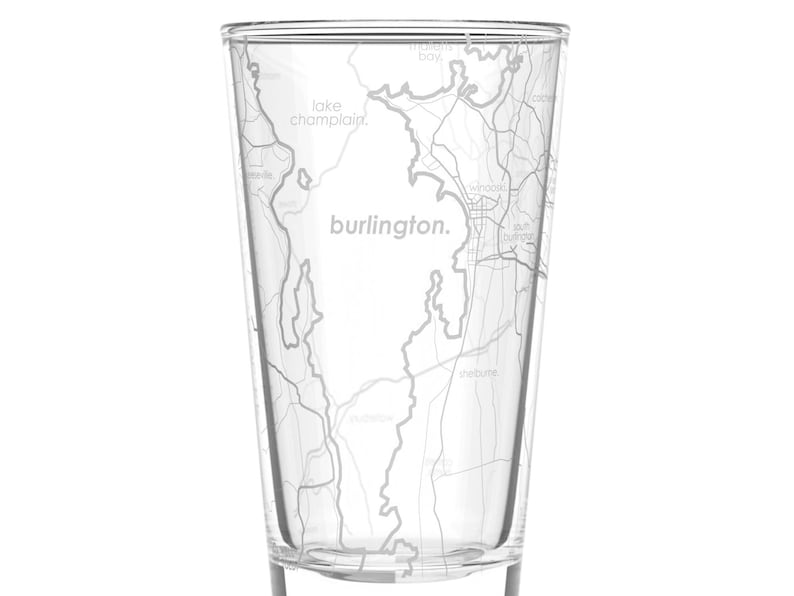 May include: A clear glass with a map of Burlington, Vermont etched on the side. The map includes the text "burlington." and "lake champlain."