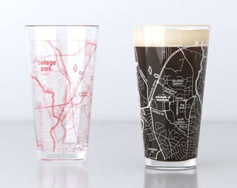 Puede incluir: Dos vasos de pinta de vidrio transparente con un mapa de College Park, Maryland impreso en ellos. Un vaso está vacío y el otro está lleno de un líquido oscuro.