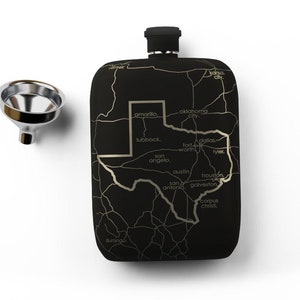 May include: Black flask with a gold outline of the state of Texas and major cities labeled. The flask has a silver funnel.