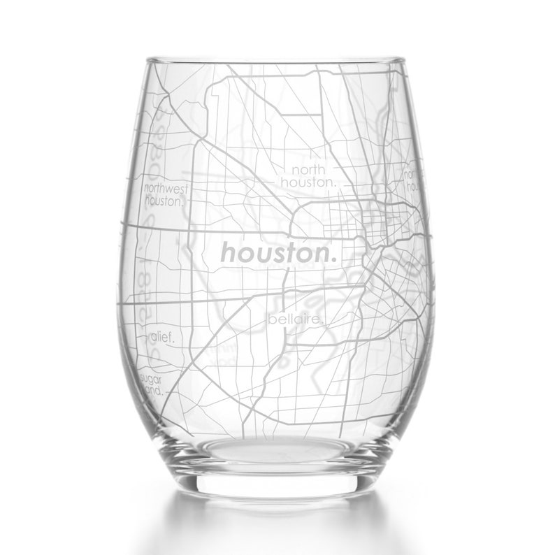 May include: A clear glass wine glass with an etched map of Houston, Texas. The map includes the names of several neighborhoods, including "northwest houston", "north houston", "houston", "alief", "bellaire", and "sugar land".