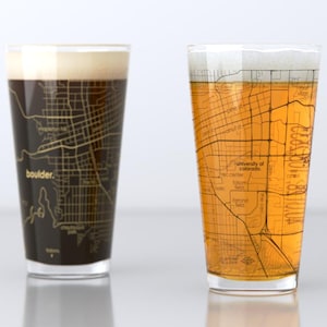May include: Two clear pint glasses with a map of Boulder, Colorado printed on the side. The glass on the left is filled with dark beer, while the glass on the right is filled with a light beer.
