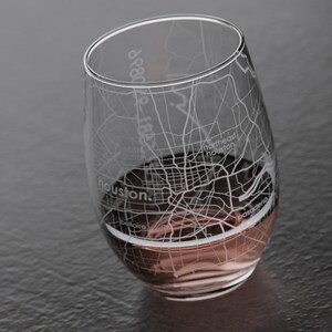 May include: A clear glass wine glass with an etched design of the Houston, Texas street map. The glass is filled with a pink beverage.