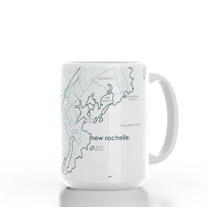 K&ouml;nnte beinhalten: Wei&szlig;e Keramiktasse mit einer Karte von New Rochelle, New York, die darauf gedruckt ist. Die Karte ist in Blaut&ouml;nen und Grau gehalten. Der Text "new rochelle." ist in Grau unter der Karte gedruckt.