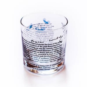 May include: A clear glass tumbler with a quote from Oscar Wilde printed on the side. The quote reads: "A delicate wind stirred amidst the trees of the garden, and honey-coloured blossoms of a laburnum that were stretched in front of the huge sense of swiftness and motion. The dim insistent"