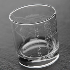 May include: A clear glass tumbler with an etched design of a city map. The map includes street names and coordinates. The coordinates are 3.076 - 82.4112.