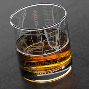 May include: A clear glass with an etched design of the Columbus, Ohio city map. The glass is filled with a golden brown liquid.