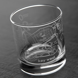 May include: A clear glass tumbler with an etched map of Key West, Florida. The map includes street names and landmarks, such as "Salt Ponds" and "Southernmost Point". The text "key west." is etched at the bottom of the glass.
