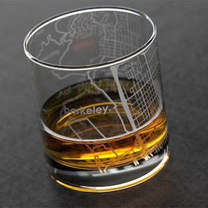 May include: A clear glass with an etched map of Berkeley, California. The glass is filled with amber-colored liquid.