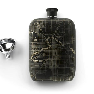 May include: Black flask with a gold map of Muncie, Indiana on the front. The flask has a silver cap and a silver funnel is next to it.