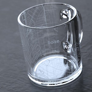 May include: A clear glass mug with a white outline of the city of Boise, Idaho etched on the side. The mug has a handle and the word "Boise." is printed on the side.