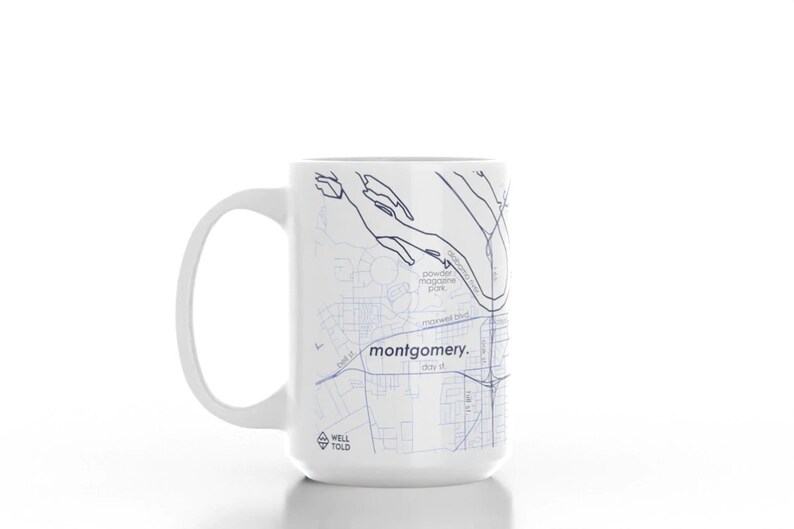 K&ouml;nnte beinhalten: Wei&szlig;e Keramiktasse mit einer blauen und wei&szlig;en Karte von Montgomery, Alabama. Die Tasse tr&auml;gt den Text "montgomery." und "WELL TOLD".
