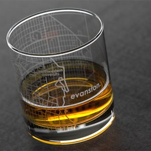 May include: A clear glass with an etched design of the Evanston, Illinois city map. The glass is filled with a golden-colored beverage and the text "northwestern university" and "evanston" are visible on the glass.