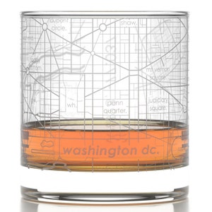 May include: A clear glass with a map of Washington D.C. etched on the side. The glass is filled with a brown liquid. The text "washington dc." is printed on the bottom of the glass.