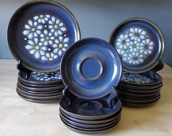 May include: A set of blue and white ceramic plates with a daisy pattern. The plates are stacked in two piles, one with larger plates and one with smaller plates.