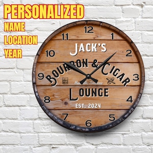 May include: A wooden clock with a brown barrel design. The clock face features the text "Jack's Bourbon & Cigar Lounge Est. 2024" with a black background and white text. The clock hands are black.