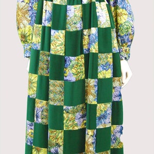 Puede incluir: Un vestido largo de color verde con estampado floral y una faja de terciopelo verde. El vestido tiene un patrón de cuadros con cuadrados verdes y cuadrados florales.