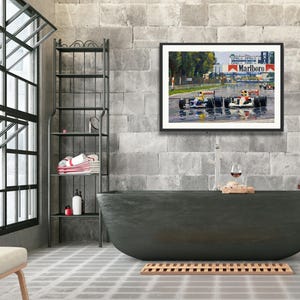 Puede incluir: Una obra de arte enmarcada que representa una carrera de F&oacute;rmula 1 bajo la lluvia, con coches en la pista. La obra cuelga sobre una ba&ntilde;era gris oscuro en un ba&ntilde;o moderno con una ventana grande y una estanter&iacute;a de metal.