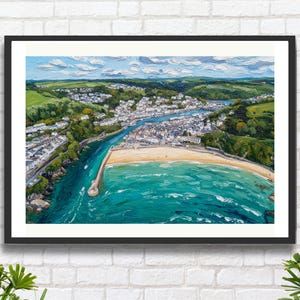Puede incluir: Pintura enmarcada de una vista aérea de un pueblo costero con playa de arena, agua turquesa y un río que desemboca en el mar. La obra de arte está enmarcada en negro y sobre una pared de ladrillos blancos.