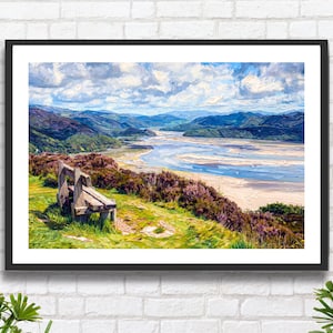 May include: A framed landscape painting depicts a scenic view of a river and mountains under a cloudy sky. A wooden bench sits on a grassy hill in the foreground, with purple bushes and green grass. The artwork is framed in a black border.