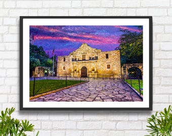 May include: A framed wall art print depicting the Alamo mission building in San Antonio, Texas. The stone structure is illuminated against a vibrant purple and pink sunset sky, with a stone-paved walkway leading to the entrance and green grass.