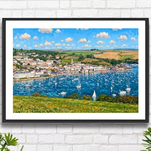 May include: A framed painting of a coastal scene, showing a town nestled beside a harbour filled with sailboats. The artwork features a blue sky with clouds, green hills, and buildings. The painting is in a black frame.