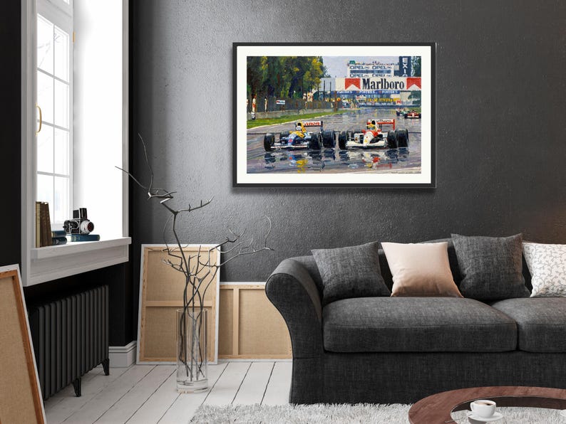 Puede incluir: Obra de arte enmarcada que representa una carrera de F&oacute;rmula 1. La pintura muestra varios coches de carreras en una pista mojada, con el logotipo de Marlboro en el fondo. La obra est&aacute; enmarcada en negro y cuelga de una pared gris oscura.