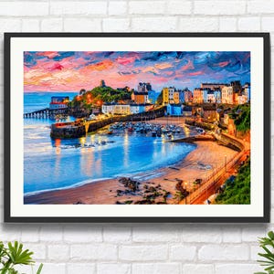 Peut inclure: Une impression d'art encadrée d'une ville côtière au coucher du soleil. La peinture représente des bâtiments colorés, un port avec des bateaux et une plage. Le ciel est un mélange de rose, d'orange et de bleu, se reflétant dans l'eau. L'œuvre est encadrée d'un cadre noir.