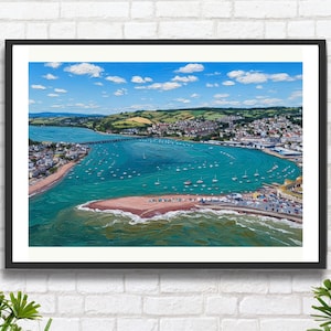 May include: Framed art print of a coastal landscape. The image shows a turquoise bay with numerous sailboats, a bridge, and a town on the shore under a blue sky with clouds. The print is in a black frame, evoking a sense of place.