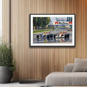 Puede incluir: Impresi&oacute;n enmarcada de una carrera de F&oacute;rmula 1 bajo la lluvia. Dos coches de carreras en primer plano, con el logotipo de Marlboro visible. La imagen est&aacute; colgada en una pared con paneles de madera.