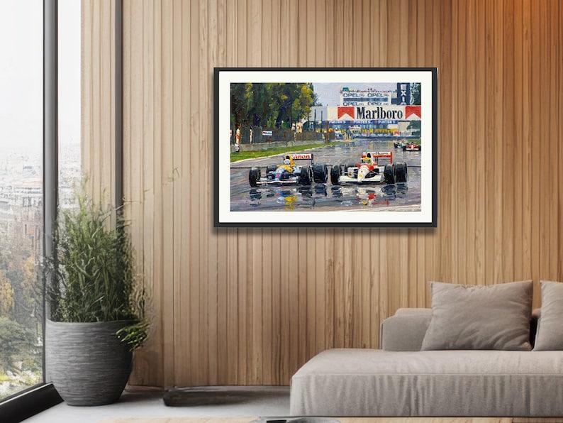 Puede incluir: Impresi&oacute;n enmarcada de una carrera de F&oacute;rmula 1 bajo la lluvia. Dos coches de carreras en primer plano, con el logotipo de Marlboro visible. La imagen est&aacute; colgada en una pared con paneles de madera.