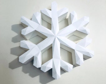 May include: A white paper snowflake ornament with a geometric design. The snowflake is made of folded paper and has a three-dimensional appearance.