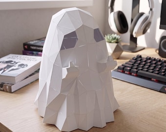 May include: A white, low-poly, geometric ghost figurine with a faceted surface. The ghost features two dark, recessed eye sockets and two small, raised arms extending outward from its sides, creating a stylized, angular appearance.