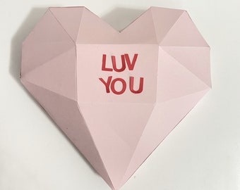 May include: A pink paper heart with the words "LUV YOU" in red letters.