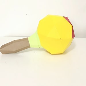 Puede incluir: Un modelo de mazo de papel amarillo y marrón con un acento rojo. El mazo está hecho de papel doblado y tiene una cabeza redonda.