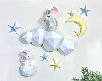 May include: A white papercraft cloud with two gray papercraft mice, one on top of the cloud and one on a smaller cloud below. The background is white with yellow and blue paper stars and a yellow crescent moon.