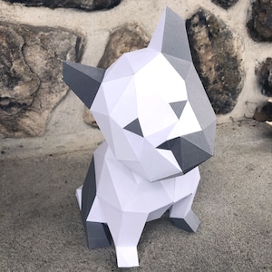 May include: A white and grey papercraft model of a sitting bulldog. The model is made of folded paper and has a geometric design.