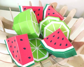 May include: A collection of paper fruit-shaped boxes in a wooden basket. The boxes are shaped like limes and watermelons and are decorated with green and red colors.