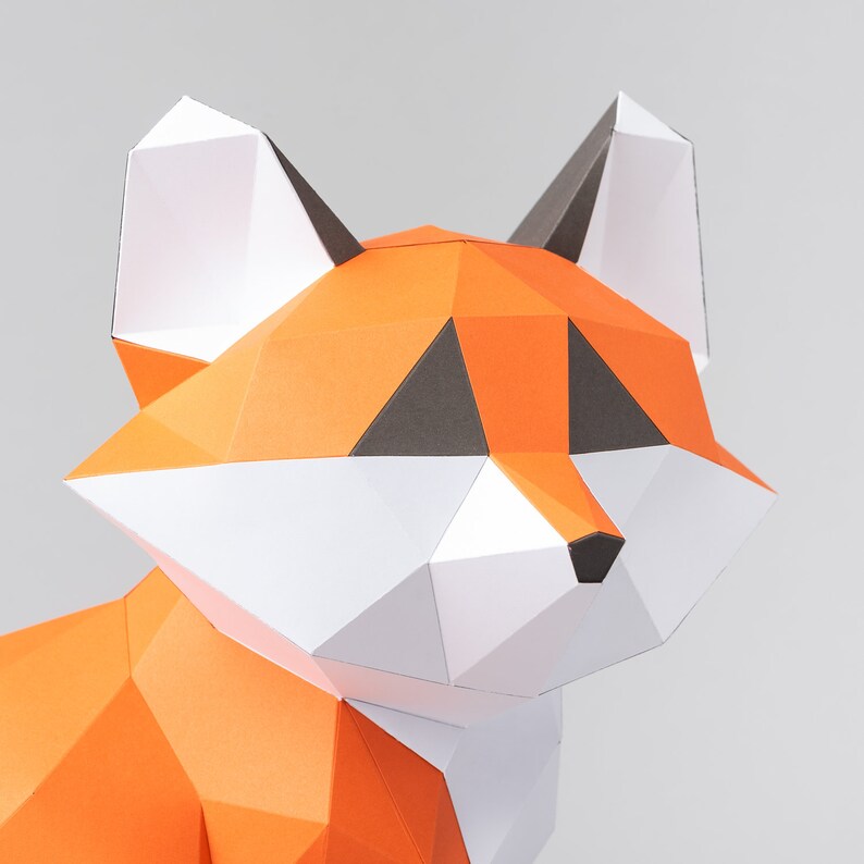 May include: A papercraft fox model with orange, white, and black paper. The fox's head is angled to the side, and its eyes are closed.