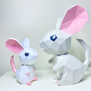 May include: Two white papercraft mice, one large and one small, with pink ears and blue eyes. The mice are posed as if they are looking at each other.