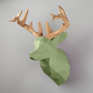 May include: A green papercraft deer head with brown paper antlers. The deer head is made of folded paper and has a geometric design.