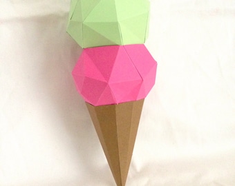 Puede incluir: Un cono de helado de papel con dos bolas de helado. La bola superior es verde claro y la bola inferior es rosa.