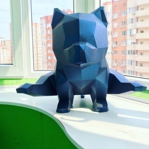 May include: A blue, geometric, origami-style sculpture of a dog. The sculpture is sitting on a white surface.