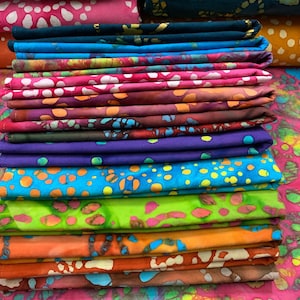 May include: A stack of colorful fabric squares with a batik pattern. The fabric is folded neatly and has a variety of colors, including pink, blue, green, orange, and purple.