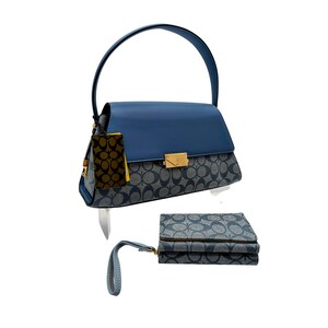 May include: A blue handbag with a solid blue top flap and a grey and blue monogram patterned body, featuring a gold-tone metal clasp and a single handle. A matching grey and blue monogram patterned wallet with a wrist strap is positioned below.
