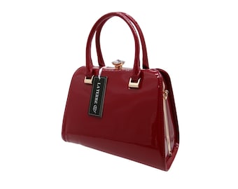 May include: A glossy dark red handbag with two top handles and a gold-toned metal frame closure topped with a clear crystal accent. A black rectangular tag hangs from the handle, featuring the white text LA TERRE and a circular logo.